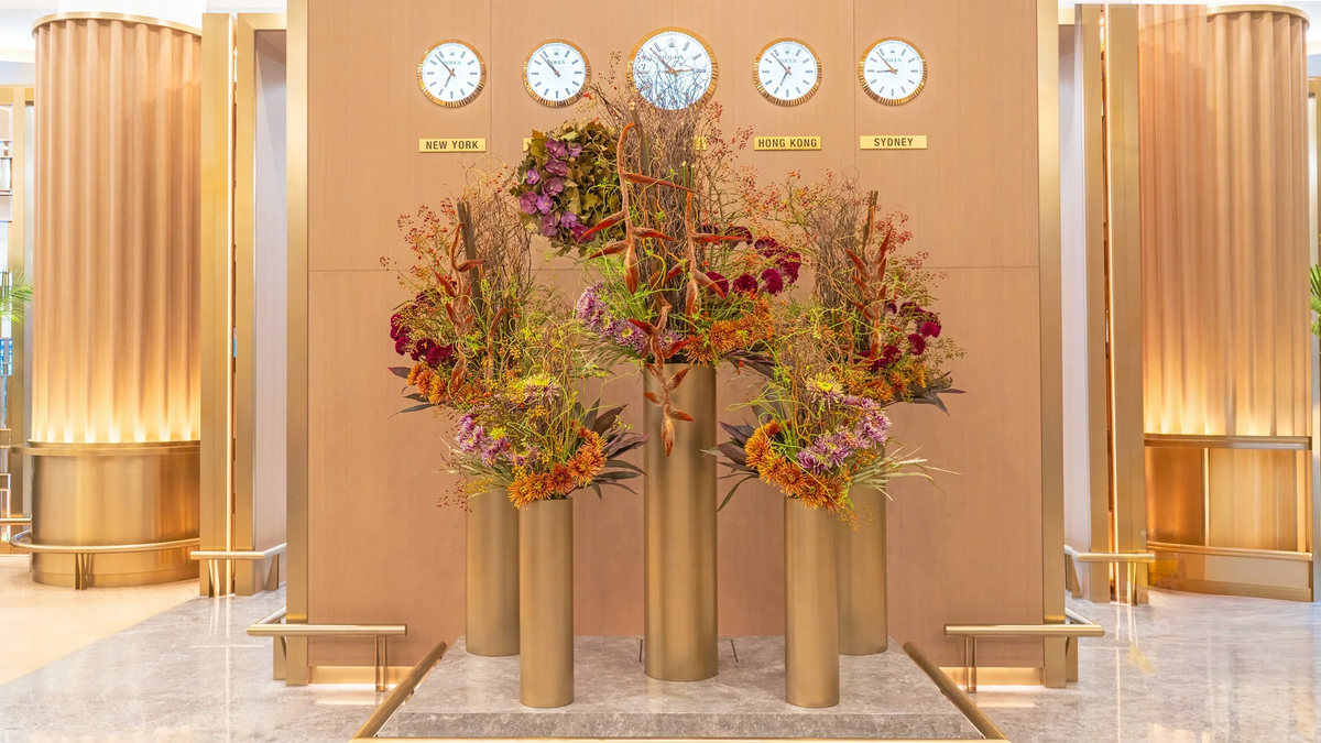 The Golden Ascent, a tall floral installation in Emirates First Class Lounge featuring Heliconia, Vanda orchids, spider chrysanthemums, and rosehips in golden and sunset tones, symbolizing Dubai’s ambition and luxury.