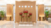 Wide view of The Royal Ornament installation in the First Class Lounge, featuring gold pedestal spheres crafted from woven Salix and filled with red Ilex and Amaryllis beneath world time clocks