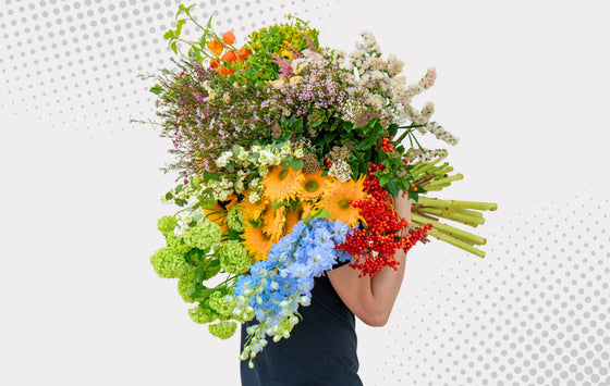 Florist holding a large bunch of colorful mixed fresh flowers and foliage.