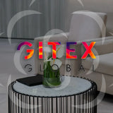 Small modern table with a glass vase of white calla lilies placed in a sleek lounge setting at GITEX Global exhibition in Dubai.