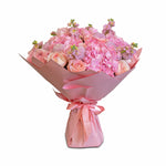 Bouquet of pink flowers wrapped in pink paper with a bow on a white background