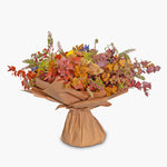 Bouquet of autumn flowers wrapped in brown paper on a white background