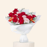 Bouquet of red and pink flowers on a white pedestal against a beige background