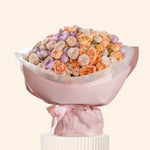 Bouquet of flowers wrapped in pink paper on a white background