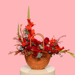 Wicker basket filled with red and orange flowers on a pink background