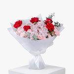Bouquet of red and pink flowers wrapped in white paper on a white background