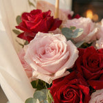Bouquet of red and pink roses with green leaves.