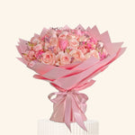 Bouquet of pink flowers wrapped in pink paper with a bow on a light background