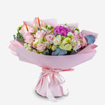 Bouquet of flowers wrapped in pink paper with a bow on a white background