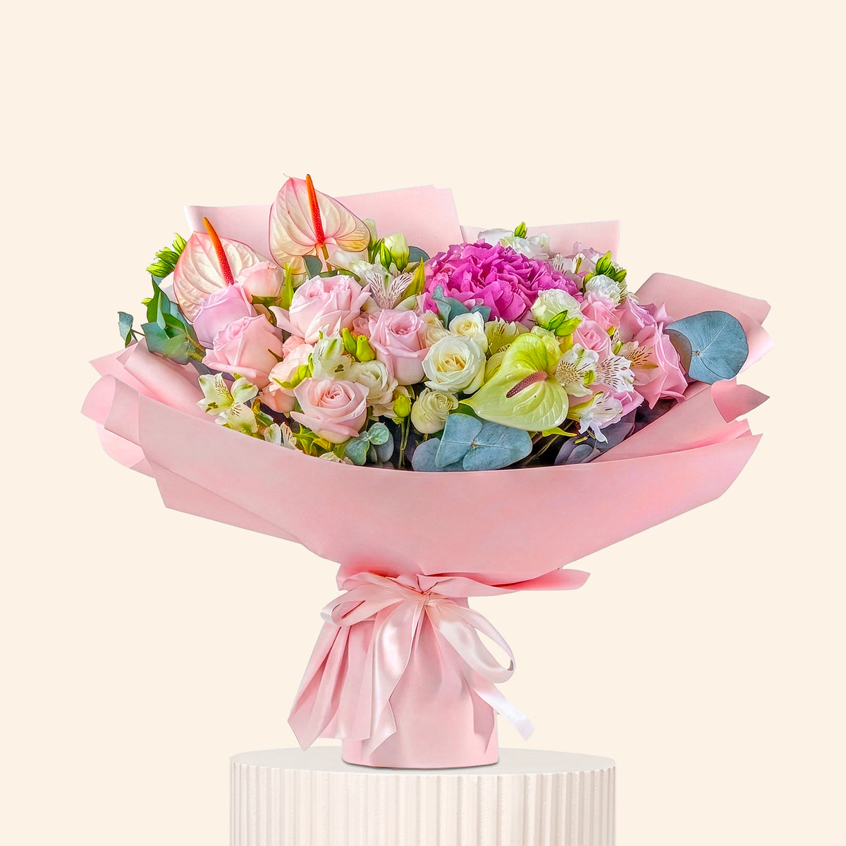 Bouquet of flowers wrapped in pink paper with a bow on a white background