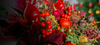 Close-up of a festive arrangement with red apples, berries, and gold leaves on a blurred background.