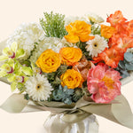 Bouquet of colorful flowers including roses and orchids on a light background