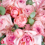 Hand-tied bouquet of soft pink roses with astilbe and eucalyptus, held in hand, fresh flower arrangement available for same-day delivery in Dubai & Sharjah.