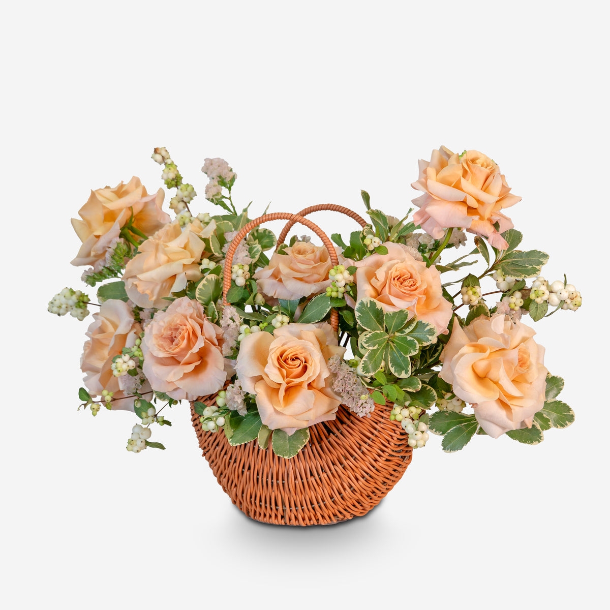 Floral arrangement with peach-colored roses in a wicker basket on a white background