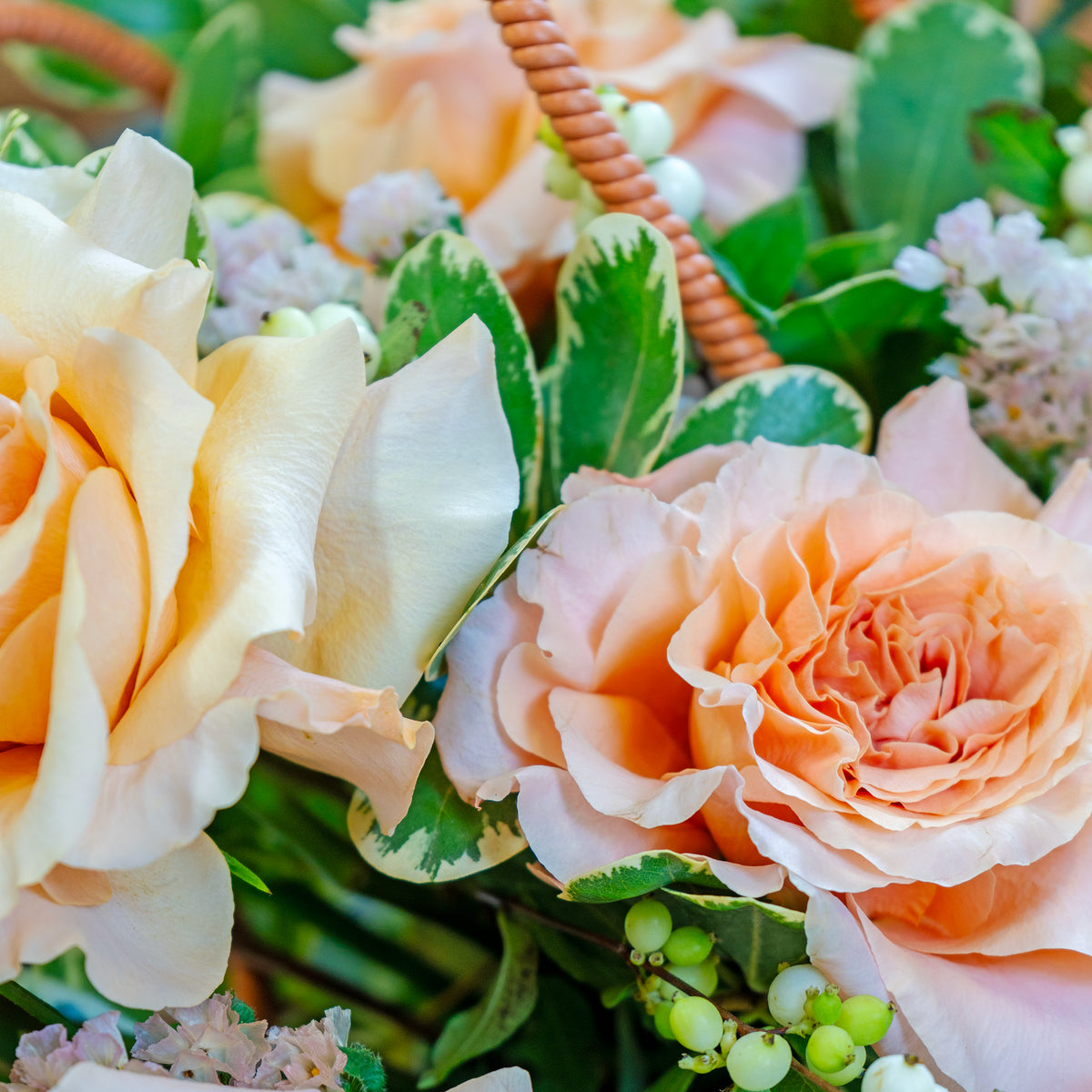 Close-up of a bouquet with peach-colored roses and green leaves.