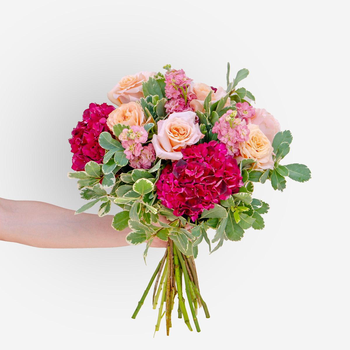 Hand-tied bouquet of peach roses, deep pink hydrangeas, and soft pink stock flowers with greenery, fresh floral arrangement in Dubai & Sharjah.