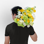 Person wearing a large floral wreath on their back against a white background