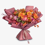 Bouquet of flowers wrapped in pink paper on a white background