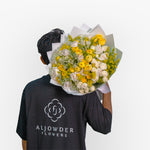 Person holding a bouquet of flowers with 'Aljowder Flowers' branding on a white background