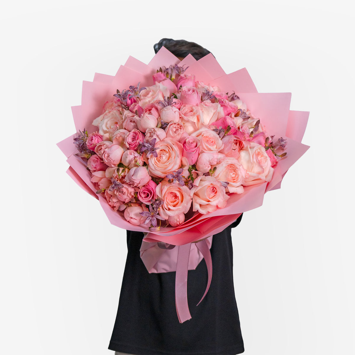 Bouquet of pink and white flowers held by a person wearing a black dress on a white background