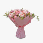 Bouquet of pink flowers wrapped in pink paper on a white background