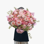 Person holding a large bouquet of pink roses against a white background