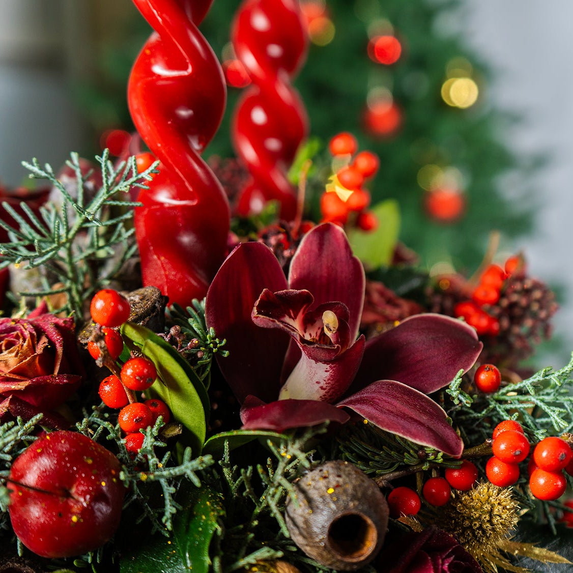 Decorative Christmas arrangement with red berries and greenery on a blurred festive background