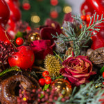 Close-up of festive decorations with red berries, gold balls, and greenery.