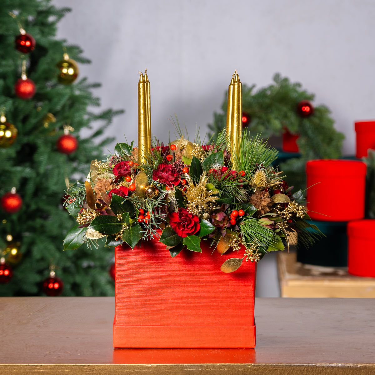 Decorative floral arrangement with candles in a red box against a festive background