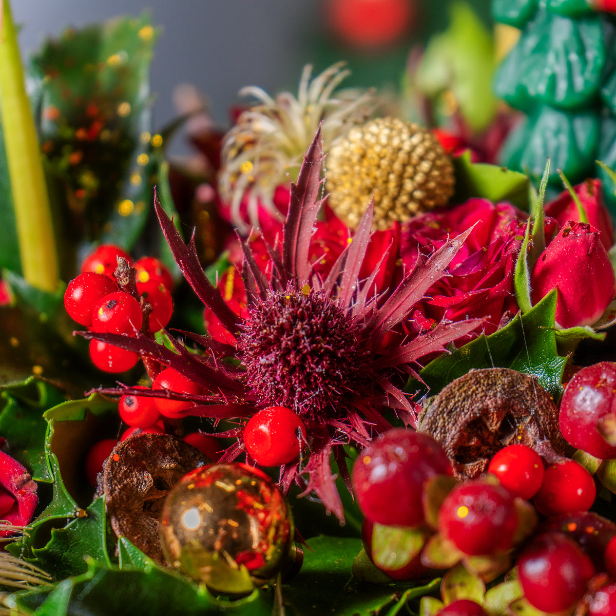 Close-up of a festive floral arrangement with red berries and green leaves.
