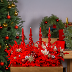 Decorative red wreath with candles and ornaments in front of a Christmas tree and wreaths.