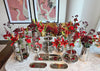 Decorative table setting with silver platters and red floral arrangements in a home interior.