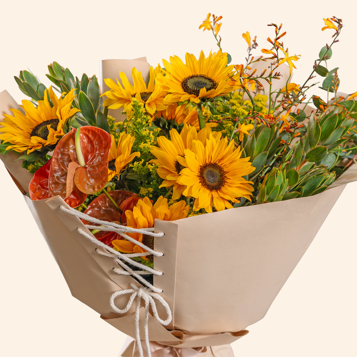 Bouquet of yellow sunflowers and greenery in a beige paper wrap on a light background