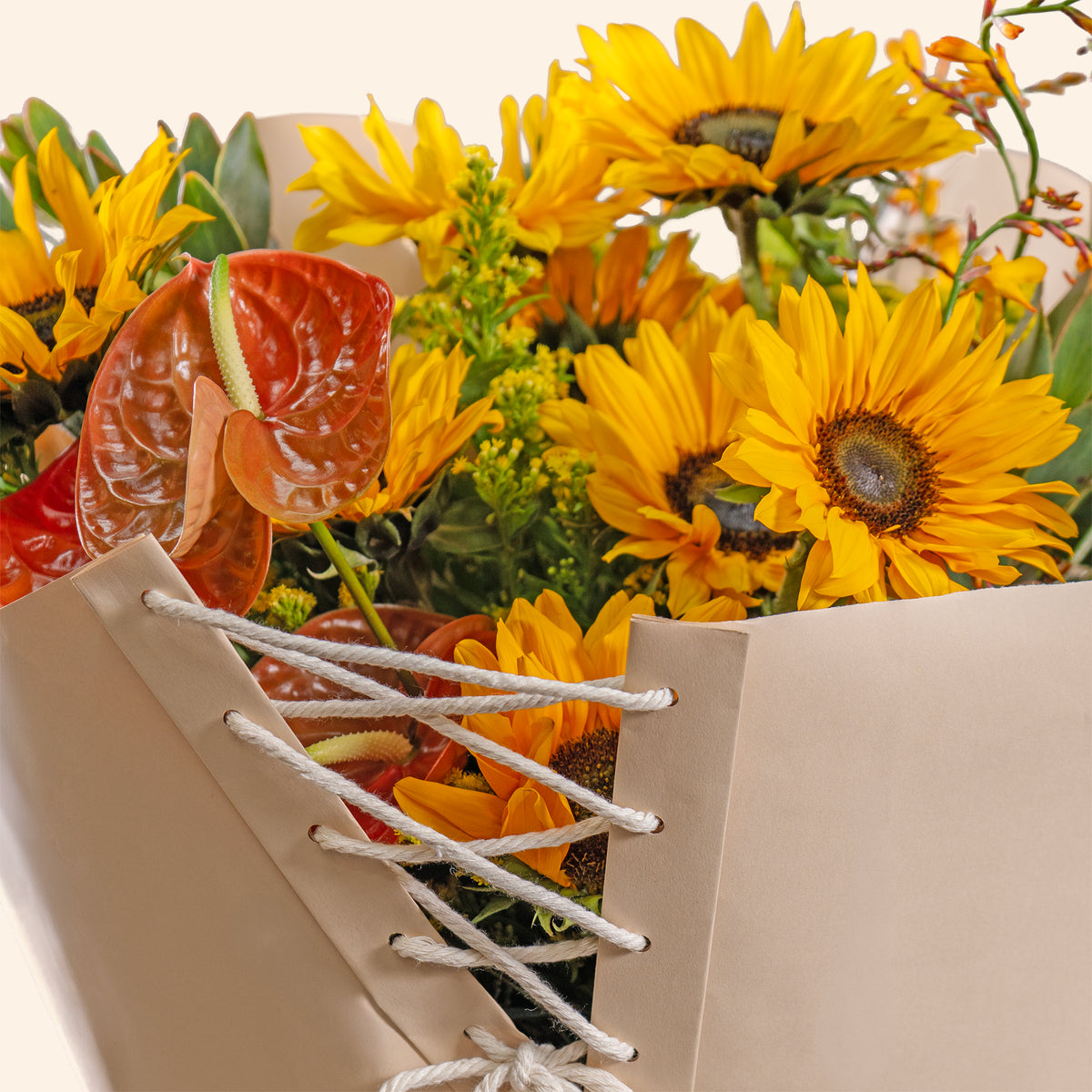 Bouquet of sunflowers and red flowers in a decorative box on a white background