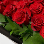 Close-up of a bouquet of red roses with green leaves.
