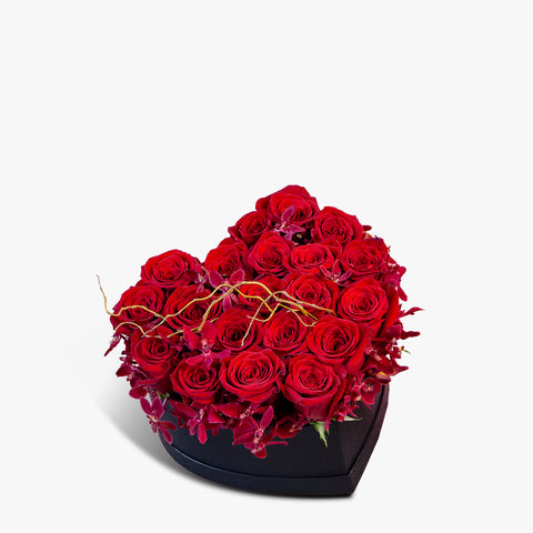 Heart-shaped arrangement of red roses in a black box on a white background