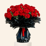 Bouquet of red roses in a black origami-style vase on a light gray background