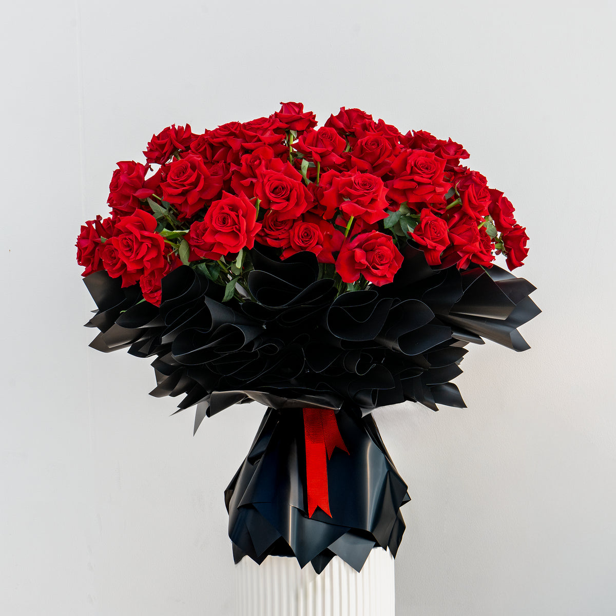 Luxury Valentine’s bouquet of red roses wrapped in black paper with red ribbon, premium romantic flower arrangement