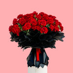 Bouquet of red roses in a black and white vase on a pink background
