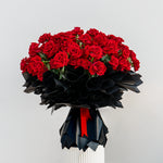 Luxury Valentine’s bouquet of red roses wrapped in black paper with red ribbon, premium romantic flower arrangement