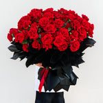 Close-up of fresh red roses bouquet with premium black wrapping, Valentine’s Day roses arrangement