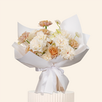 Bouquet of flowers wrapped in white paper with a white ribbon on a light beige background