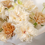 Close-up of a bouquet of white and beige flowers on a light background