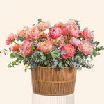 Bouquet of pink flowers in a woven basket on a light beige background