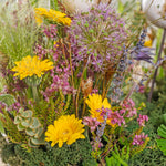 Close-up of a bouquet of yellow and purple flowers with greenery