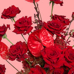 Bouquet of red roses and red anthuriums on a pink background