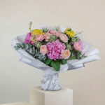 Bouquet of flowers wrapped in white paper on a beige background