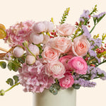 Bouquet of pink and white flowers in a white vase on a light beige background