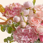 Close-up of a bouquet of pink and white flowers with green leaves on a light background