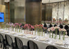 Long table set for a formal event with floral centerpieces and silverware.
